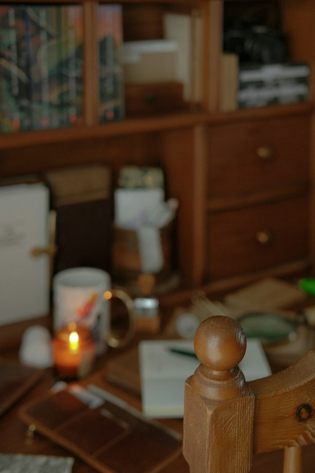 Old wooden writing desk with typewriter, notebook and candle in dim light