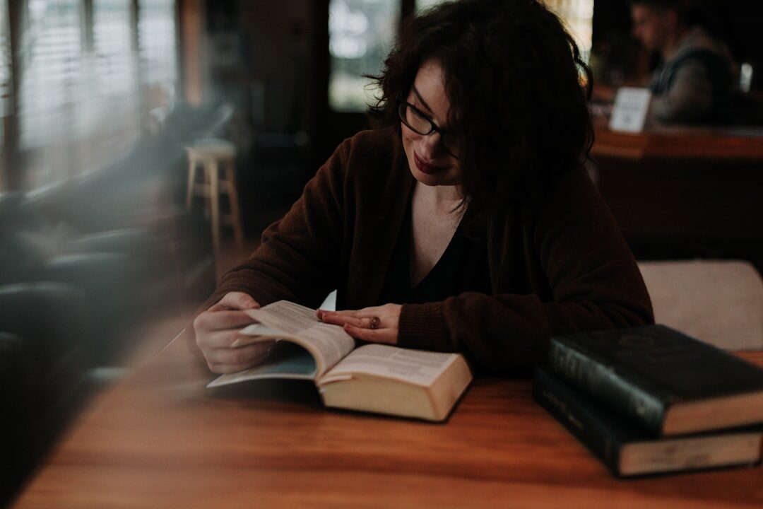 Young Croatian woman reading a hardcover novel in a cafe